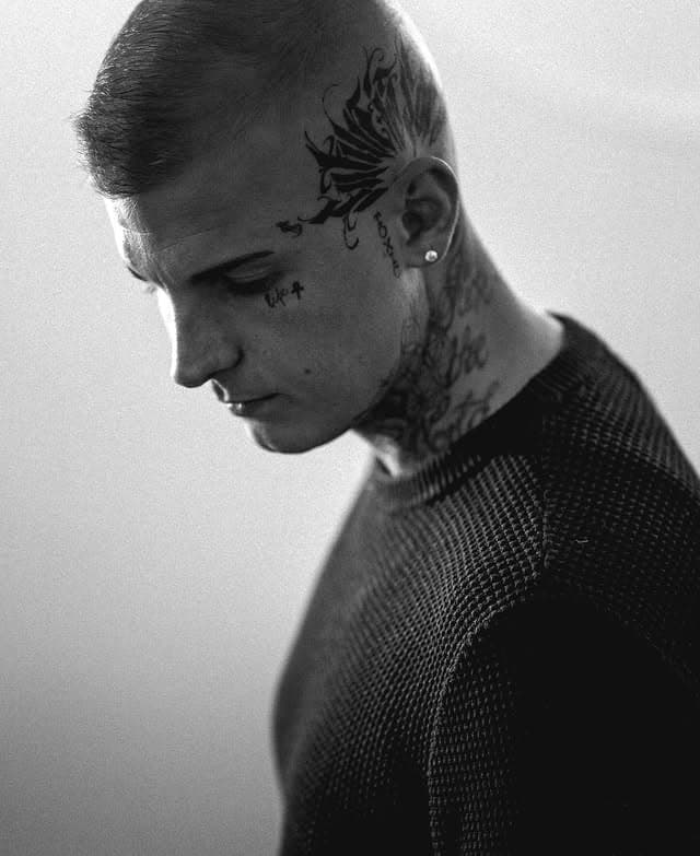 Porträt im Profil, Schwarzweiß, Tattoos an Schläfe und Hals