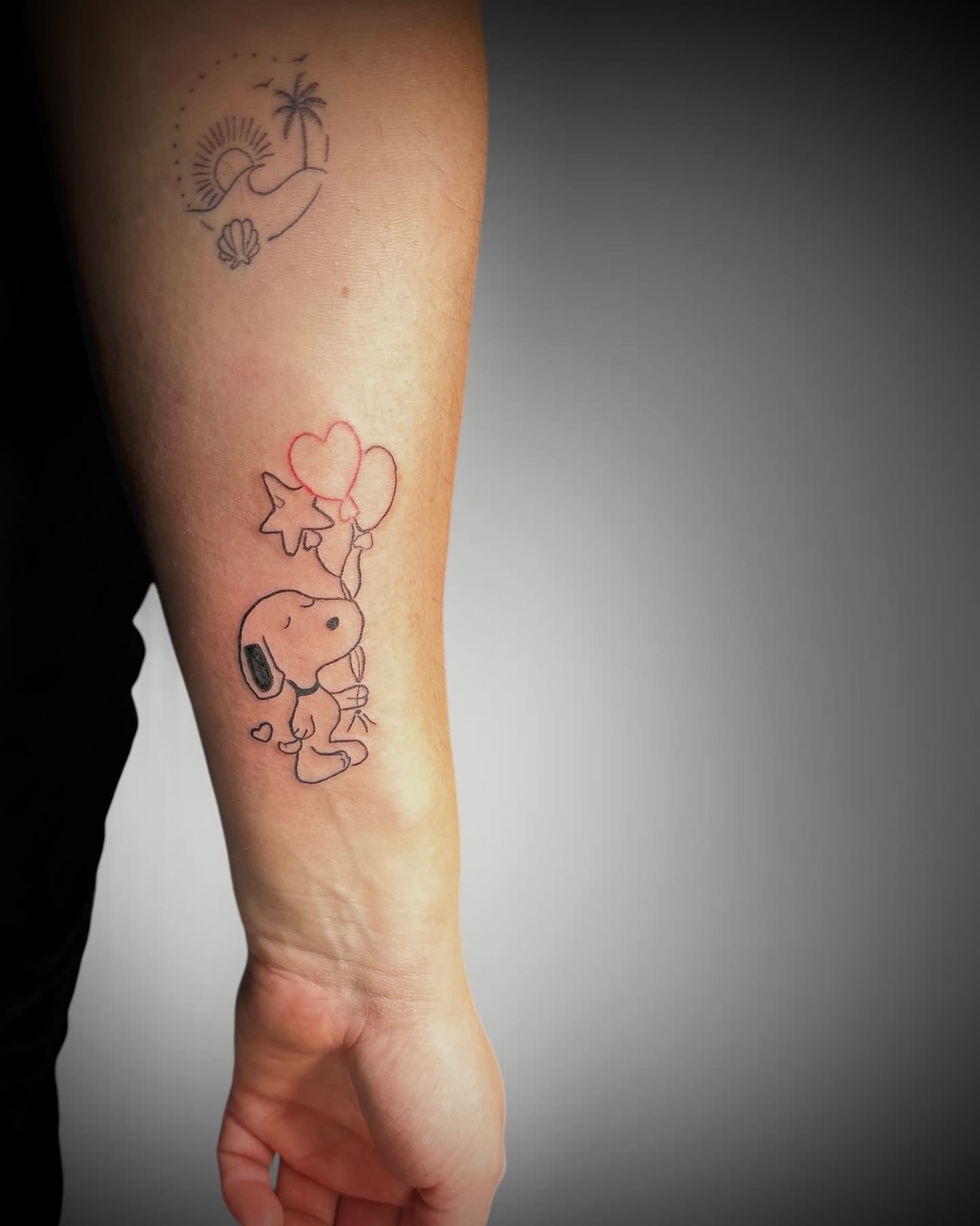 Feiner Snoopy mit roten Herzballons über dem Handgelenk